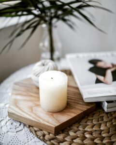 pexels-photo-2402326-2402326 A calming still life with a candle, magazine, and plant on a textured surface indoors.